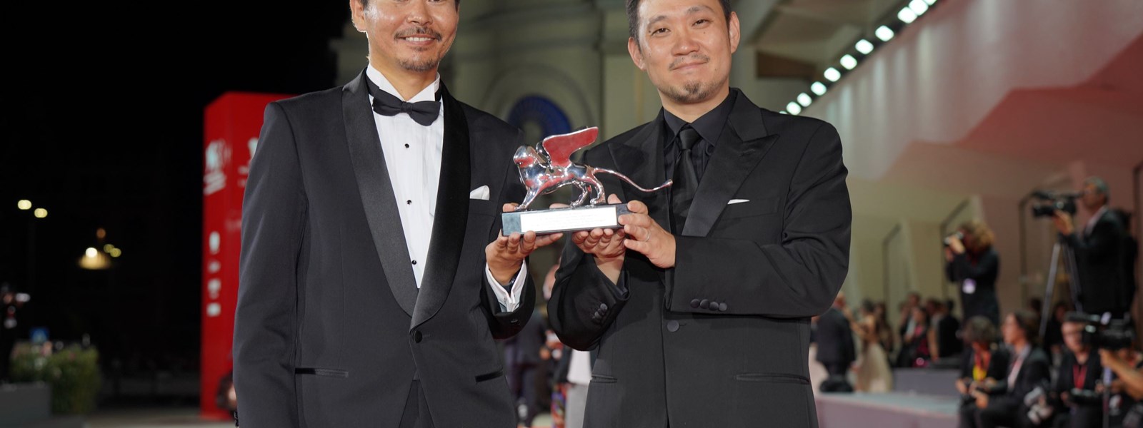  ريوسوكي هاماغوتشي مع ممثّله هيتوشي أوميكا بعد فوزه بجائزة لجنة التحكيم الكبرى في مهرجان البندقية 2023. 