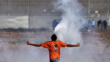 متظاهر فلسطيني يحمل قنبلة غاز مسيل للدموع أطلقتها القوات الإسرائيلية خلال تظاهرة على الحدود شرق غزة، في ذكرى الانسحاب الإسرائيلي من القطاع عام 2005 (13 ايلول 2023، أ ف ب). 