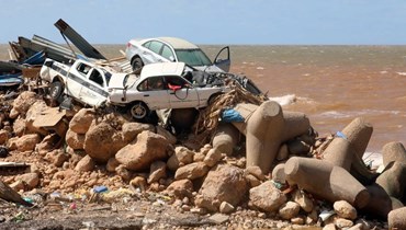 السيارات مكدّسة فوق قواطع الأمواج وأنقاض مبنى دُمّر جرّاء الفيضانات في مدينة درنة بشرق ليبيا (أ ف ب). 