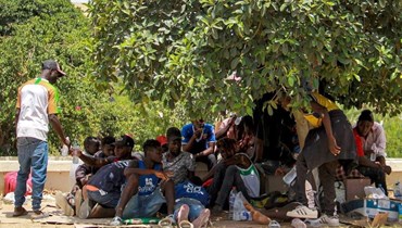 صورة تعبيرية وأرشيفية- مهاجرون من جنوب الصحراء الكبرى يستريحون تحت شجرة خلال احتجاج على الظروف القاسية التي يواجهونها في مدينة صفاقس الساحلية وسط تونس (7 تموز 2023، أ ف ب).