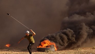 متظاهر فلسطيني يستخدم مقلاعا لإلقاء الحجارة على الجنود الإسرائيليين خلال مسيرة بالقرب من السياج الحدودي بين إسرائيل وغزة (22 ايلول 2023، أ ف ب).