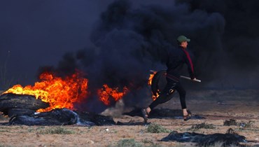 متظاهر فلسطيني يحرق الإطارات خلال اشتباكات مع جنود إسرائيليين شرق رفح في جنوب قطاع غزة بالقرب من السياج الحدودي (23 ايلول 2023، أ ف ب). 