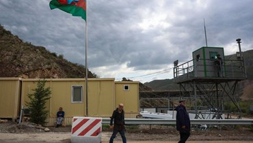 لاجئون يمرون بالقرب من علم أذربيجان عند نقطة تفتيش لاتشين (26 ايلول 2023، أ ف ب).
