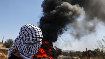 متظاهر يقف بالقرب من إطارات مشتعلة أثناء اشتباكه مع عناصر من القوات الإسرائيلية في قرية كفر قدوم، في الضفة الغربية المحتلّة (أ ف ب). 
