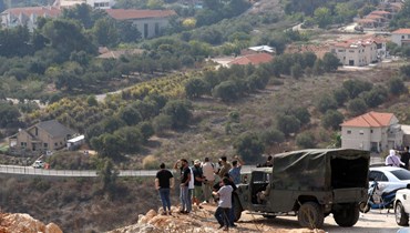 جنود لبنانيون ومواطنون يرصدون من خلف الخط الأزرق الحدودي، الحركة في الجهة المقابلة داخل المستوطنات الإسرائيلية. (أ ف ب)