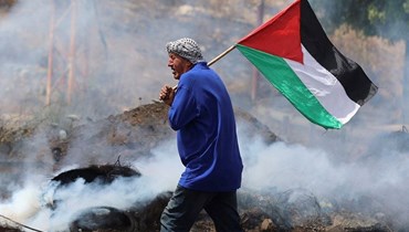 رجل يرفع علم فلسطين وسط الركام. (أ ف ب)
