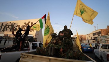 عناصر من حركة النجباء الشيعية في العراق يلوحون بالعلم الفلسطيني خلال مسيرة في بغداد دعما لعملية طوفان الأقصى (8 ت1 2023، أ ف ب).