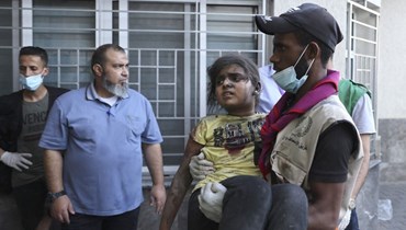 رجل ينقل طفلة جريحة إلى مستشفى الشفاء بمدينة غزة (10 ت1 2023ـ أ ف ب).