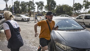 أشخاص يركضون للاختباء عند سماع صفارات الإنذار في مدينة عسقلان بجنوب إسرائيل (11 ت1 2023، أ ف ب). 