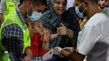 مسعفون ينقلون طفلاً فلسطينياً مصاباً إلى مستشفى الشفاء في مدينة غزة (أ ف ب). 