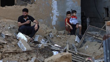 فلسطينيون وقفوا وسط اضرار خلفتها غارة إسرائيلية على مخيم رفح للاجئين في جنوب قطاع غزة (15 ت1 2023، أ ف ب).