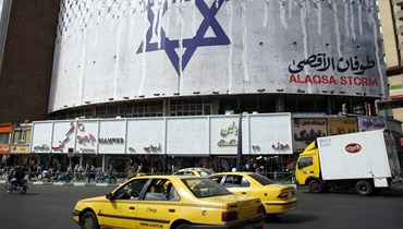 إيرانيّون يقودون سياراتهم بالقرب من لوحة إعلانية مناهضة لإسرائيل (أ ف ب). 