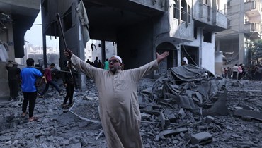 فلسطيني وقف وسط أنقاض مبنى بعد غارة جوية إسرائيلية على مخيم رفح للاجئين في جنوب قطاع غزة (17 ت1 2023، ا ف ب). 