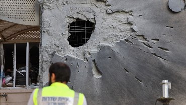 عنصر من خدمات الطوارئ يتفقد مبنى بمدينة سديروت جنوب إسرائيل اصيب  بصاروخ أطلق من غزة (17 ت1 2023، أ ف ب).