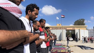 متطوعون مصريون يؤدّون الصلاة أمام معبر رفح من الجانب المصري بانتظار إدخال المساعدات إلى قطاع غزّة (أ ف ب).