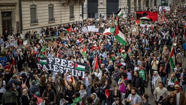 متظاهرون يلوحون بالأعلام الفلسطينية خلال مسيرة لدعم غزة في جنيف (14 ت1 2023 - أ ف ب).