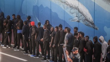 صورة ارشيفية- مهاجرون وقفوا بالصف في ميناء لوس كريستيانوس في جزيرة تينيريفي بعد نزولهم من سفينة "تابورينتي" (12 ت1 2023، أ ف ب). 