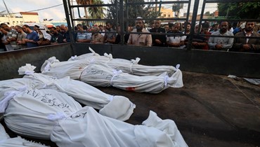 أشخاص يؤدون الصلاة قرب جثث قتلى الغارات الإسرائيلية، خارج مشرحة مستشفى الأقصى في دير البلح وسط قطاع غزة (22 ت1 2023، أ ف ب). 
