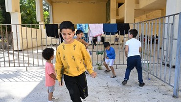 أولاد يلعبون في ملعب مدرسي في صور بعدما نزحوا مع ذويهم من القرى الحدودية ولجأوا إلى أماكن نزوح في القرى والمدن البعيدة نسبياً عن القصف. (حسام شبارو)