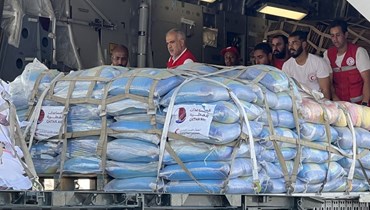 متطوّعون من المنظّمات الإنسانية التابعة للهلال الأحمر القطري والمصري يقومون بتفريغ المساعدات المتجهة إلى قطاع غزة (أ ف ب).