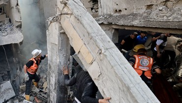 رجال إنقاذ يبحثون عن ناجين بين أنقاض مبنى أصيب في غارة إسرائيلية في خان يونس بجنوب قطاع غزة (24 ت1 2023، أ ف ب).