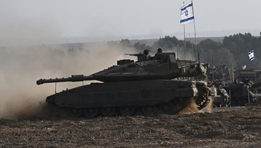 دبابة ميركافا إسرائيلية تنتشر مع مدرعات أخرى على طول حدود إسرائيل مع غزة (24 ت1 2023، أ ف ب).
