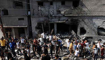 فلسطينيون يبحثون عن ناجين بين أنقاض مبنى أصيب في غارة إسرائيلية في خان يونس بجنوب قطاع غزة (24 ت1 2023، أ ف ب).