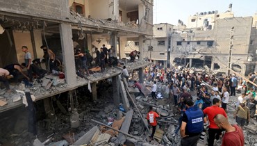 فلسطينيون يبحثون عن ناجين بين أنقاض مبنى أصيب في غارة إسرائيلية في خان يونس بجنوب قطاع غزة (24 ت1 2023، أ ف ب).