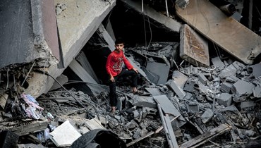 صبيّ يقف وسط أنقاض مبنى في أعقاب هجوم إسرائيلي على مدينة غزة (26 ت1 2023 - أ ف ب).