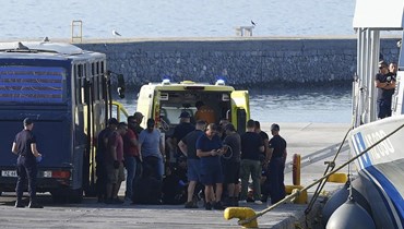 صورة ارشيفية- مهاجرون تم انقاذهم جلسوا قرب سيارة إسعاف في ميناء ميتيليني على جزيرة ليسبوس باليونان (28 آب 2023، أ ب). 
