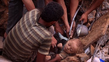 فلسطينيون ينتشلون جثة طفل من تحت أنقاض مبنى في مخيم النصيرات للاجئين وسط قطاع غزة (31 ت1 2023، أ ف ب). 