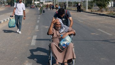 أشخاص يصلون إلى وسط قطاع غزة مشيا عبر طريق صلاح الدين في طريقهم إلى الجزء الجنوبي من القطاع الفلسطيني (5 ت2 2023، أ ف ب).