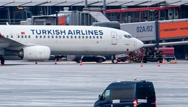 سيارة للشرطة تراقب سيارة محتجز رهينة توقفت قرب طائرة تابعة للخطوط الجوية التركية على مدرج المطار في مطار هامبورغ شمال ألمانيا (5 ت2 2023، أ ف ب).