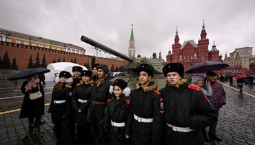 طلاب عسكريون يقفون مع فنان يرتدي الزي العسكري للحرب العالمية الثانية في متحف تفاعلي في الهواء الطلق في الساحة الحمراء في موسكو (7 ت2 2023، أ ف ب). 
