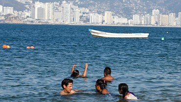سكان في أكابولكو يستمتعون بشواطئ تلاكوبانوتشا وسط ارتفاع الحرارة بعد مرور الإعصار "أوتيس" في أكابولكو بولاية غيريرو بالمكسيك (5 ت2 2023، أ ف ب). 