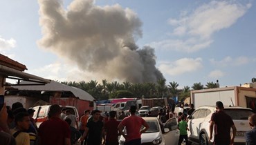 فلسطينيون ينظرون الى دخان يتصاعد بعد قصف إسرائيلي في خان يونس جنوب قطاع غزة (8 ت2 2023، أ ف ب). 