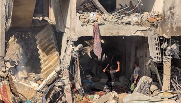 أشخاص يبحثون عن ناجين وجثث ضحايا بين أنقاض مبنى تعرض لقصف إسرائيلي في خان يونس جنوب قطاع غزة (8 ت2 2023، أ ف ب).