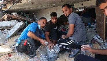 فلسطينيون يبحثون عن ناجين وضحايا عالقين تحت انقاض مبنى في أعقاب قصف إسرائيلي على رفح في جنوب قطاع غزة (10 ت2 2023ـ أ ف ب).