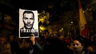 متظاهر يحمل صورة لرئيس الوزراء الإسباني بيدرو سانشيز مع عبارة "خائن"، خلال احتجاج في مدريد (10 ت2 2023 - أ ف ب).