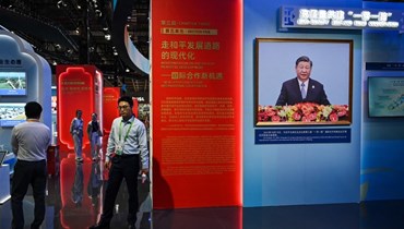 صورة لشي رفعت بينما يزور اشخاص جناح الصين خلال معرض الصين الدولي السادس للاستيراد في شنغهاي (5 ت2 2023، أ ف ب).