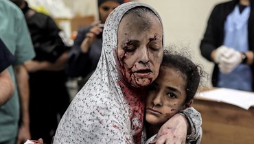 امرأة فلسطينية مصابة تُعانق طفلة مصابة في المستشفى عقب القصف الإسرائيلي على خان يونس، جنوب قطاع غزة (15 ت2 2023 - أ ف ب).