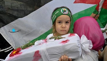 طفلة متضامنة مع غزّة ترفع مجسّماً لضحايا المجازر الإسرائيلية في وقفة أمام السفارة المصرية في بيروت (نبيل اسماعيل).