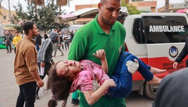مسعف فلسطيني ينقل فتاة مصابة إلى مستشفى شهداء الأقصى في دير البلح وسط قطاع غزة (19 ت2 2023، أ ف ب). 
