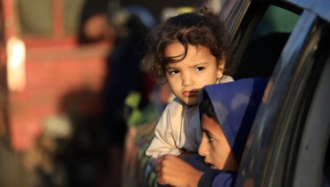 أطفال ينظرون من نافذة سيارة بينما يعود الفلسطينيون الذين لجأوا إلى ملاجئ موقّتة إلى منازلهم في شرق خان يونس بجنوب قطاع غزة خلال الساعات الأولى من الهدنة (أ ف ب). 