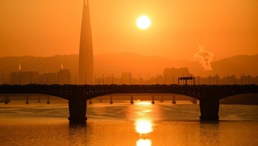 برج لوتي (الى يسار) عند شروق الشمس فوق نهر هان في سيول (22 ت2 2023، أ ف ب).
