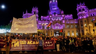 متظاهرون يحملون لافتات كتب عليها "النسويات مع الفلسطينيين" و"انتهى الأمر" في مدريد. (أ ف ب)