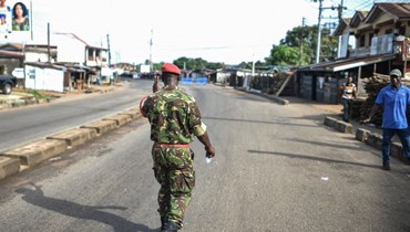 جندي من الشرطة العسكرية السيرالونية يمشي على طريق مقفر في فريتاون (26 ت2 2023، أ ف ب).