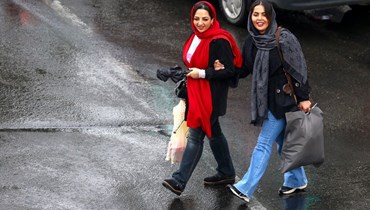 نساء إيرانيات يمشين في شارع بطهران خلال يوم ممطر (28 ت2 2023، أ ف ب). 