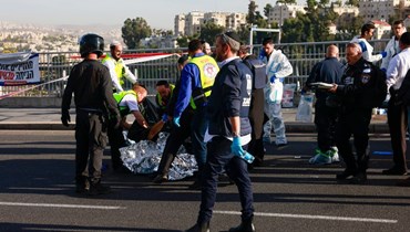 مسعفون إسرائيليّون يغطّون جثة في موقع إطلاق نار في القدس بالقرب من مستوطنة راموت (أ ف ب). 