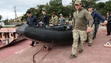 عسكريون أميركيون يحملون زورقا خلال توجههم للبحث عن الطائرة الأميركية في جزيرة ياكوشيما بمحافظة كاجوشيما (1 ك1 2023، أ ف ب).